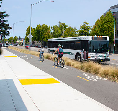Bicyclists on bike path riding past a bus.