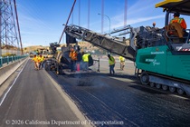 Heavy equipment and shovels are used to apply new roadway surface material as part of the bridge deck rehabilitation project on the Al Zampa Bridge on August 22, 2026.