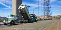 A truck unloads new material for repaving the roadway as part of the bridge deck rehabilitation project on the Al Zampa Bridge on August 22, 2026.