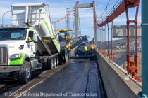 Caltrans uses trucks and heavy equipment to apply new roadway surface material on the Alfred Zampa Memorial Bridge on August 23, 2026.