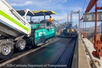 Caltrans uses heavy equipment to apply new roadway surface material on the Alfred Zampa Memorial Bridge on August 23, 2026.
