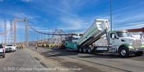 Caltrans uses trucks and heavy equipment to apply new roadway surface material on the Alfred Zampa Memorial Bridge on August 23, 2026.