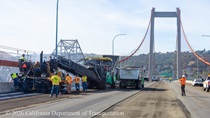 Caltrans uses trucks and heavy equipment to apply new roadway surface material on the Alfred Zampa Memorial Bridge on August 23, 2026.