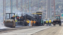 Caltrans uses trucks and heavy equipment to install the new roadway surface on the Alfred Zampa Memorial Bridge on August 23, 2026.