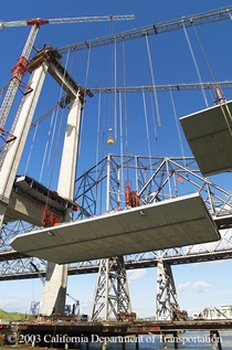 A section of the concrete bridge deck is raised into place during the construction of the Al Zampa Memorial Bridge (Carquinez Bridge Western Span).