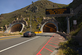 Entrance to the Tom Lantos Tunnel (also known as the Devil's Slide Tunnel) in San Mateo County. There is a changeable message sign that reads "AVOID GATHERINGS YOUR ACTIONS SAVE LIVES".
