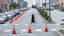 Pedestrian crossing a crosswalk as cars travel on 19th Avenue (State Route 1) as Caltrans is resurfacing the existing asphalt pavement on Northbound 19th Avenue from Sloat Boulevard to Lincoln Way as work continues on the19th Avenue Paving and Rehabilitation project.