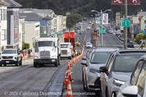 Cars travel in lane one of southbound 19th Avenue (State Route 1) as Caltrans uses trucks of asphalt in the repaving of the other lanes as work continues on the 19th Avenue Paving and Rehabilitation project on May 9, 2026..