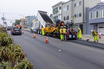 A Caltrans crew uses heavy equipment to apply new asphalt on southbound 19th Avenue (State Route 1) on May 10, 2026. The left lane remains open to vehicle traffic.