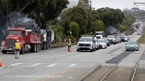 Caltrans crew directing traffic as cars cross an intersection on 19th Avenue (State Route 1) as Caltrans is using heavy equipment to resurface the existing asphalt pavement on Southbound/Northbound 19th Avenue from Sloat Boulevard to Holloway Avenue as work continues on the third of three weekend closures for the 19th Avenue Rehabilitation Project.