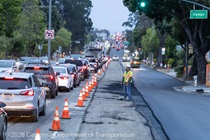 Caltrans crew standing next to cars traveling on 19th Avenue (State Route 1) as Caltrans is resurfacing the existing asphalt pavement on Southbound/Northbound 19th Avenue from Sloat Boulevard to Holloway Avenue as work continues on the third of three weekend closures for the 19th Avenue Rehabilitation Project.