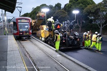 Caltrans crew using heavy equipment to prepare and resurface the existing asphalt pavement as a Muni train passes by on Southbound/Northbound 19th Avenue from Sloat Boulevard to Holloway Avenue as work continues on the third of three weekend closures for the 19th Avenue Rehabilitation Project.