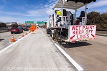 A Caltrans crew uses a vehicle to paint new lines on the roadway of eastbound I-80 in San Francisco on April 19, 2026. A sign on the back of the vehicle warns "Wet Paint Keep Off Lines".