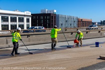 Caltrans crews finishing up the newly completed polyester overlay on the WB I-80 Bayshore Freeway as cars drive by on the open lanes on October 24, 2026. The purpose of this closure is to perform the polyester overlay of the Bayshore viaduct between 4th street and the I-80/US-101 interchange.