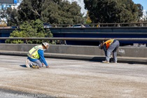 Caltrans crews finishing up the newly completed polyester overlay on the WB I-80 Bayshore Freeway as cars drive by on the open lanes on October 24, 2026. The purpose of this closure is to perform the polyester overlay of the Bayshore viaduct between 4th street and the I-80/US-101 interchange.