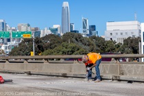 Caltrans crews finishing up the newly completed polyester overlay on the WB I-80 Bayshore Freeway as cars drive by on the open lanes on October 24, 2026. The purpose of this closure is to perform the polyester overlay of the Bayshore viaduct between 4th street and the I-80/US-101 interchange.