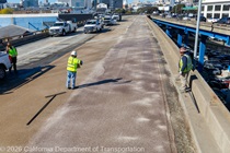 Caltrans crews finishing up the newly completed polyester overlay on the WB I-80 Bayshore Freeway as cars drive by on the open lanes on October 24, 2026. The purpose of this closure is to perform the polyester overlay of the Bayshore viaduct between 4th street and the I-80/US-101 interchange.