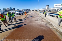 Caltrans crews finishing up the newly completed polyester overlay on the WB I-80 Bayshore Freeway as cars drive by on the open lanes on October 24, 2026. The purpose of this closure is to perform the polyester overlay of the Bayshore viaduct between 4th street and the I-80/US-101 interchange.