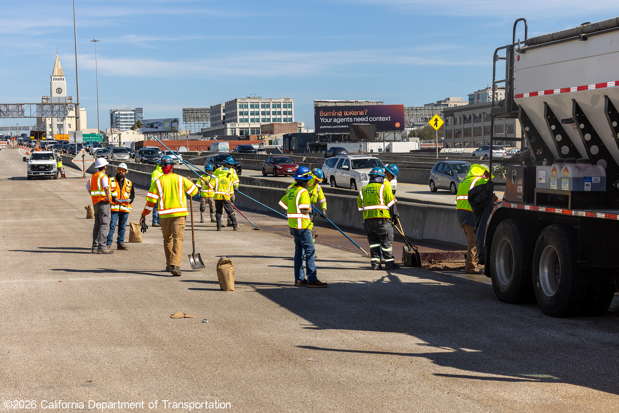 Caltrans crew with heavy equipment applying the polyester overlay on WB I-80 Bayshore Freeway as cars drive by in the open lanes on October 25, 2026. The purpose of this closure is to perform the polyester overlay of the Bayshore viaduct between 4th street and the I-80/US-101 interchange.