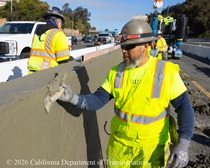 A Caltrans crewmember performs finishing work on the fresh concrete of the new median barrier on US 101 in San Francisco.