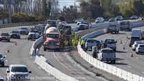 A mixer truck and heavy equipment are used to construct the new median barrier on US 101 in San Francisco while traffic continues to flow on either side of the project.