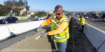 Caltrans crew member performs finishing work on the fresh concrete for the new median barrier as part of the US 101 Hospital Curve Rehabilitation Project on March 28, 2026.