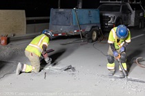 Crew members use hand tools as part of the removal of the old roadway on southbound US-101 during the night of October 16, 2026.