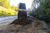 A truck dumps a load of dirt in the work area at the State Route 84 slide repair project in San Mateo County.