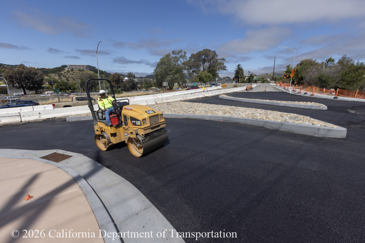 Caltrans using a smooth drum roller to compact new asphalt as part of the roundabout project at Manuel T. Freitas Parkway/US-101 interchange.