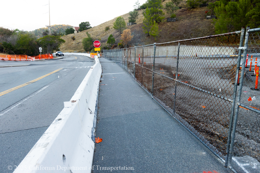 Car approaching the unfinished roundabout section with barriers as Caltrans crew works on the roundabout project at Manuel T. Freitas Parkway/US-101 interchange.