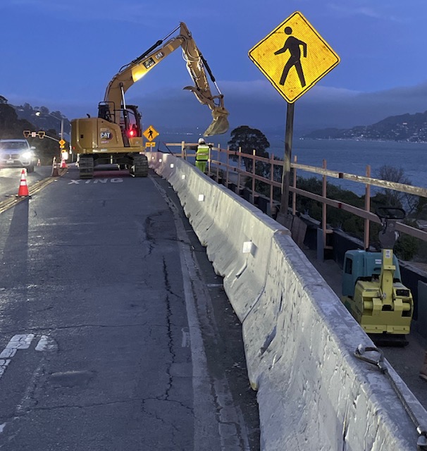 Cars travelling on State Route 131 next to Caltrans using heavy equipment preparing for construction of new retaining wall on State Route 131 (Tiburon Boulevard) Retaining Wall Project at Stewart Drive.