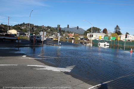 Photograph of flooding at the Manzanita/SR-1 intersection. There is a white car sitting in the water.