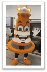 Photograph of the Caltrans mascot Safety Sam. Safety Sam is an anthropomorphic traffic cone wearing a hardhat with three orange lights on top.