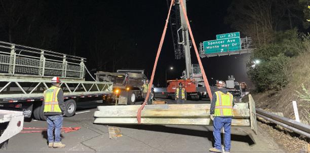 Caltrans workers and heavy machinery lifting part of a sign for sign structure project in Sausalito.