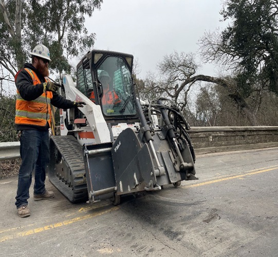 Caltrans maintenance crew uses heavy machinery to work on a roadway.