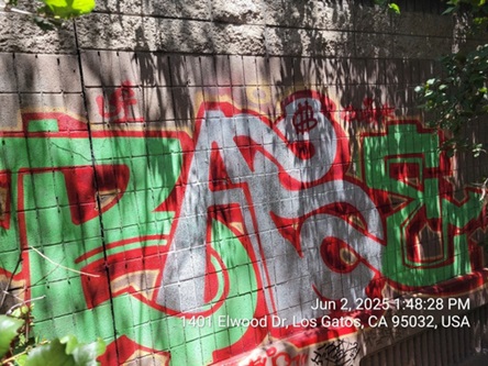 Photograph of a soundwall near Elwood Drive in Los Gatos before graffiti removal. There is a large work of graffiti on the soundwall.