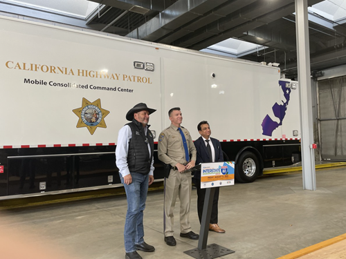 Solano County Supervisor Mitch Mashburn, a CHP officer, and Caltrans District Deputy Direct Design Wajahat Nyaz stand behind a podium. A California Highway Patrol trailer is behind the three.