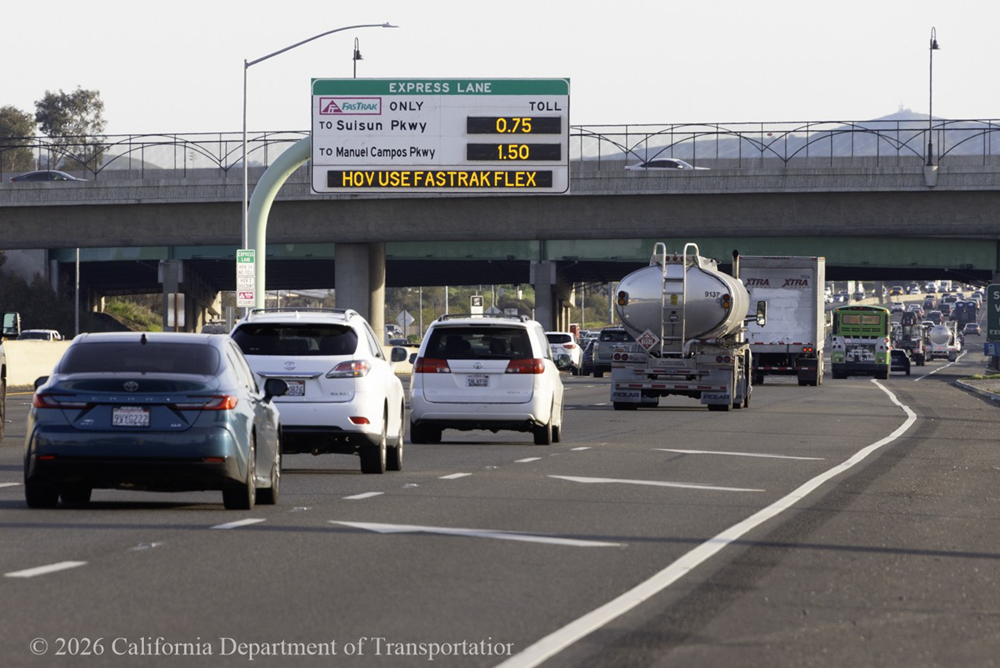 Vehicles travel on Interstate 80 in Solano County. A sign above the roadway shows information about using the express lane.