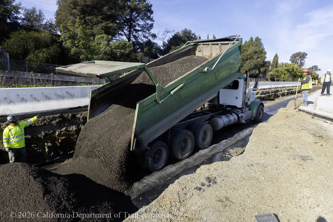 A Caltrans crew member issues instructions as a truck dumps its load as part of the divergent diamond project in Vallejo.