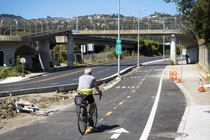 Photo by  Sergio Ruiz. Photo shows a person riding their bike on a bike route near State Route 13.  