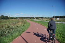 Photo by Maurits Lopes Cardozo. Photo shows a bike path with grass on either side in the Netherlands.
