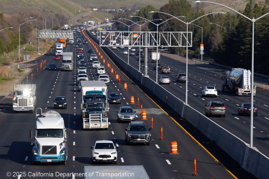 Traffic flows on westbound Interstate 80 in Solano County between Vacaville and Fairfield. Cones block traffic from entering the new lane.