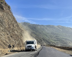Photo of hill showing stabilizing material and a truck cleaning the road at the project site