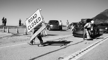 Black and white photo of staff moving road closed sign and cones officially opening highway 1 in Big Sur