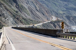 Photo showing CHP and another car driving on the reopened Highway 1 next to Regent's slide