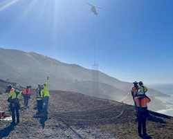 Photo of Caltrans staff directing helicopter with material to project site.