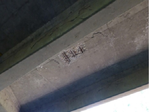 Photo of bridge soffit distress, with exposed rebar, cracks and salt residue.