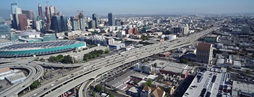 Busy multi-lane freeway with metropolitan buildings.