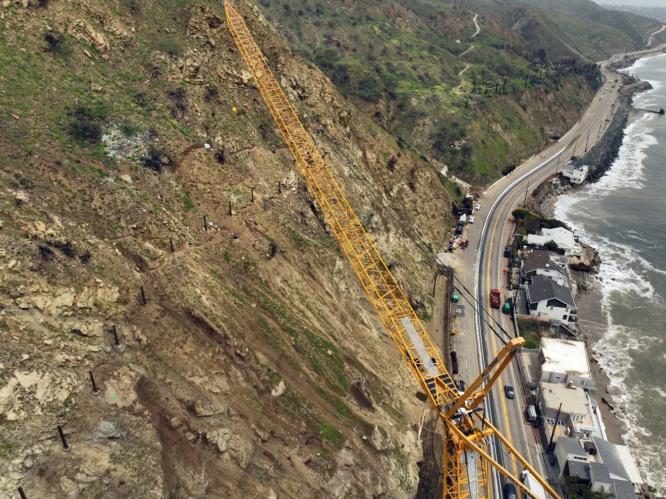 Bird view of Pacific Coast Highway. Crane repair on hillside.