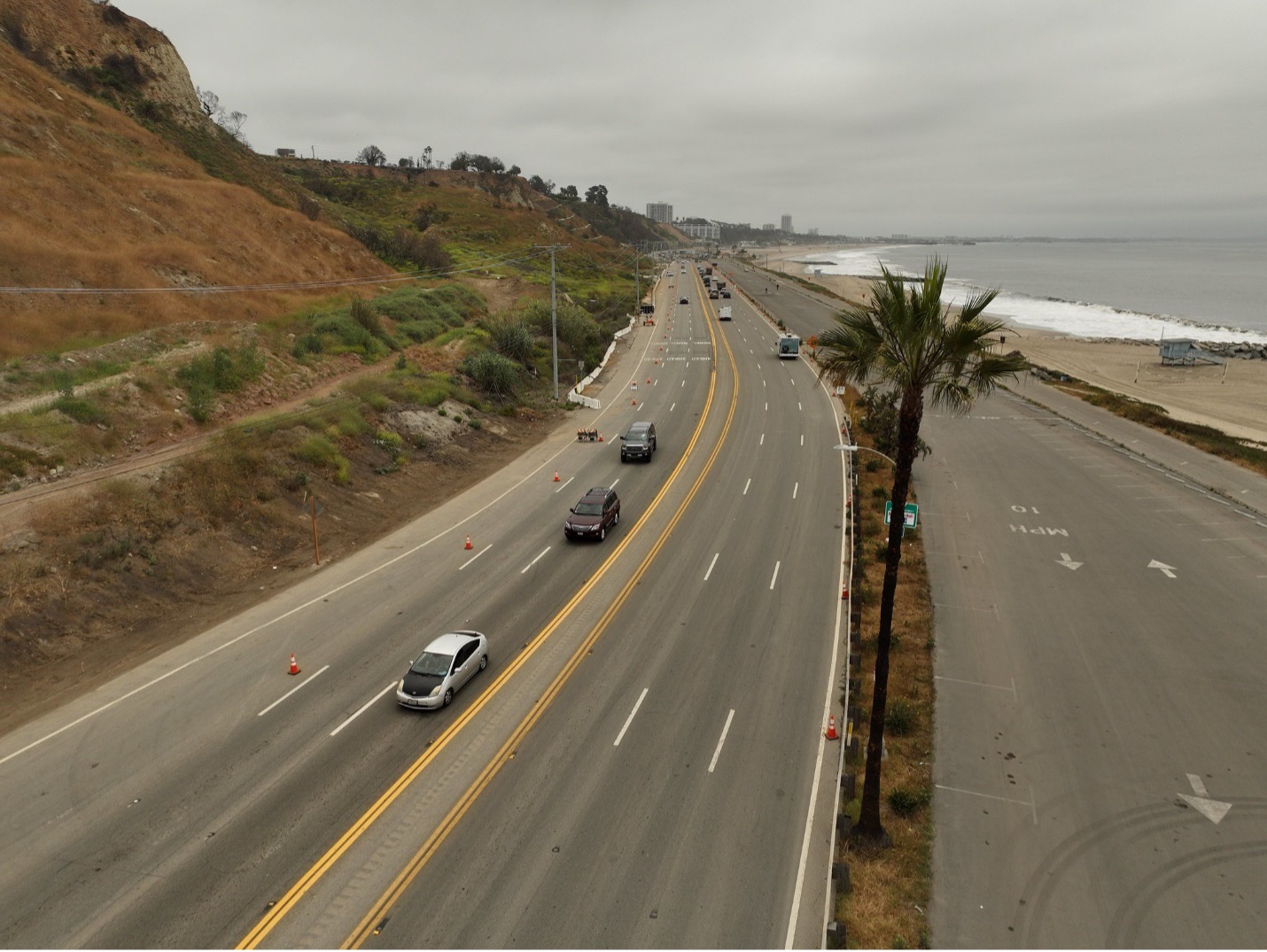 Cars driving on a segment of Pacific Coast Highway/State Route 1 in the Palisades burn zone area.